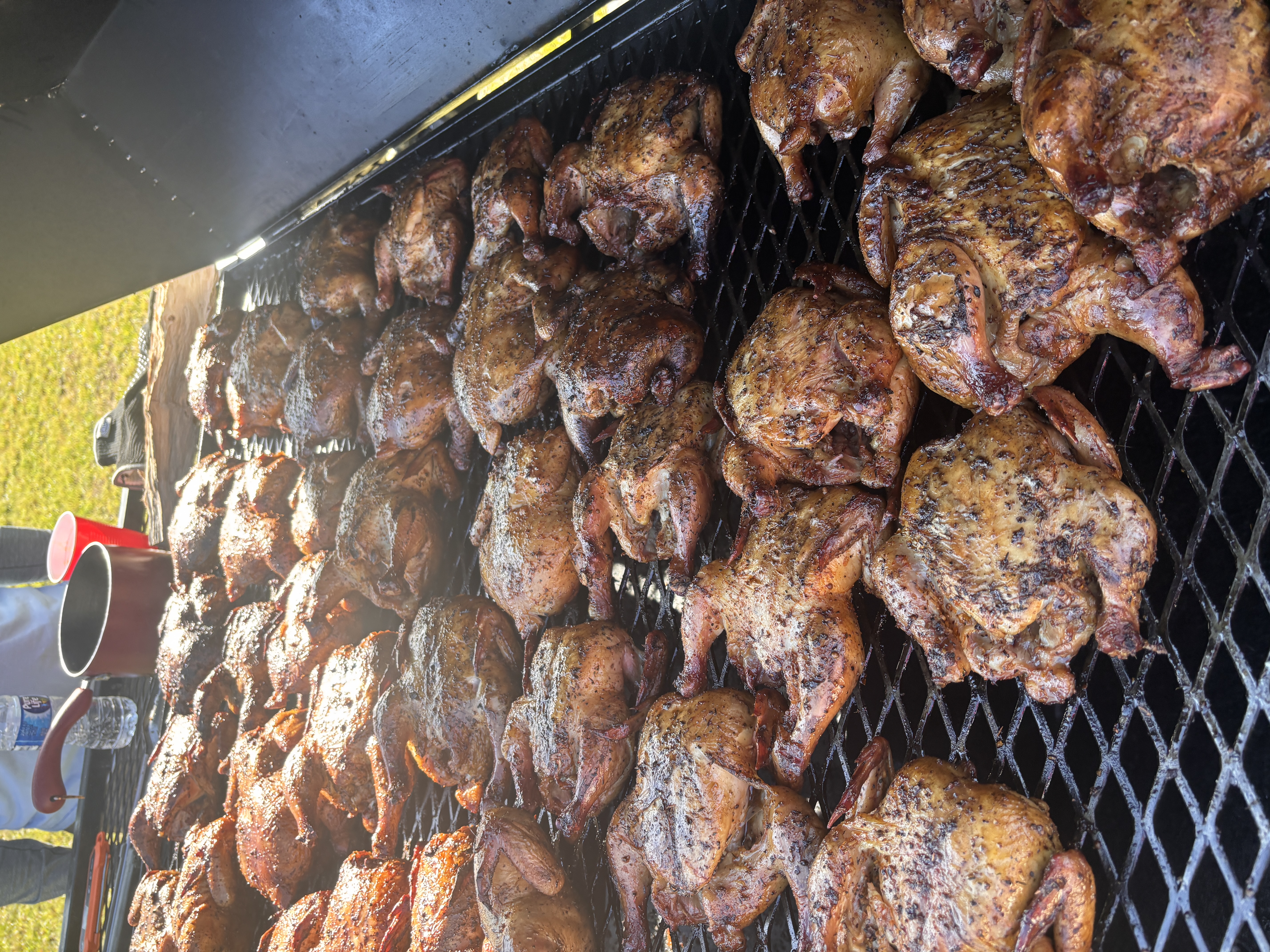 Rows of smoked chicken quarters on the grill grate