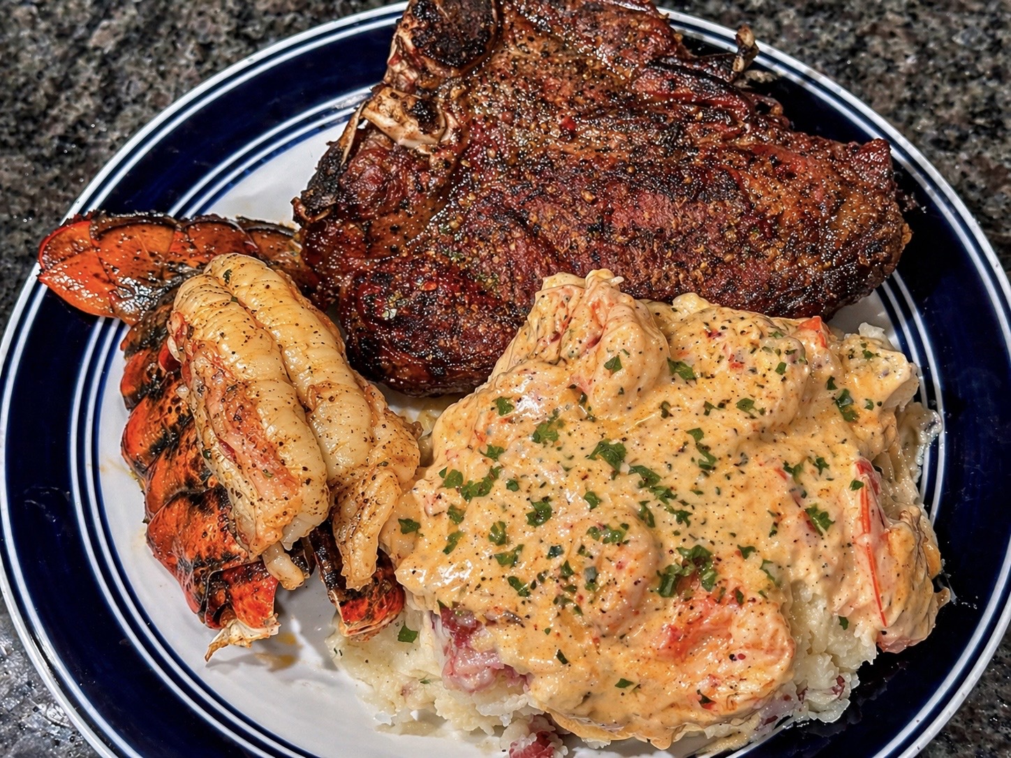 Surf and turf plate with steak, lobster, and shrimp in a creamy sauce